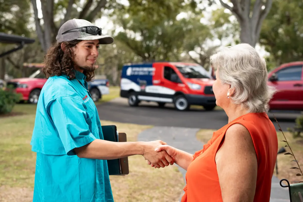 Air Conditioner Installation 6 A Custom Air Conditioning Air Quality technician shakes hands with a customer outside her home with a branded company van visible in the background