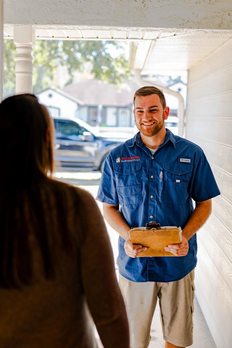 HVAC Maintenance Plan 2 Custom Air Conditioning Air Quality technician smiles while speaking with a customer at her front door