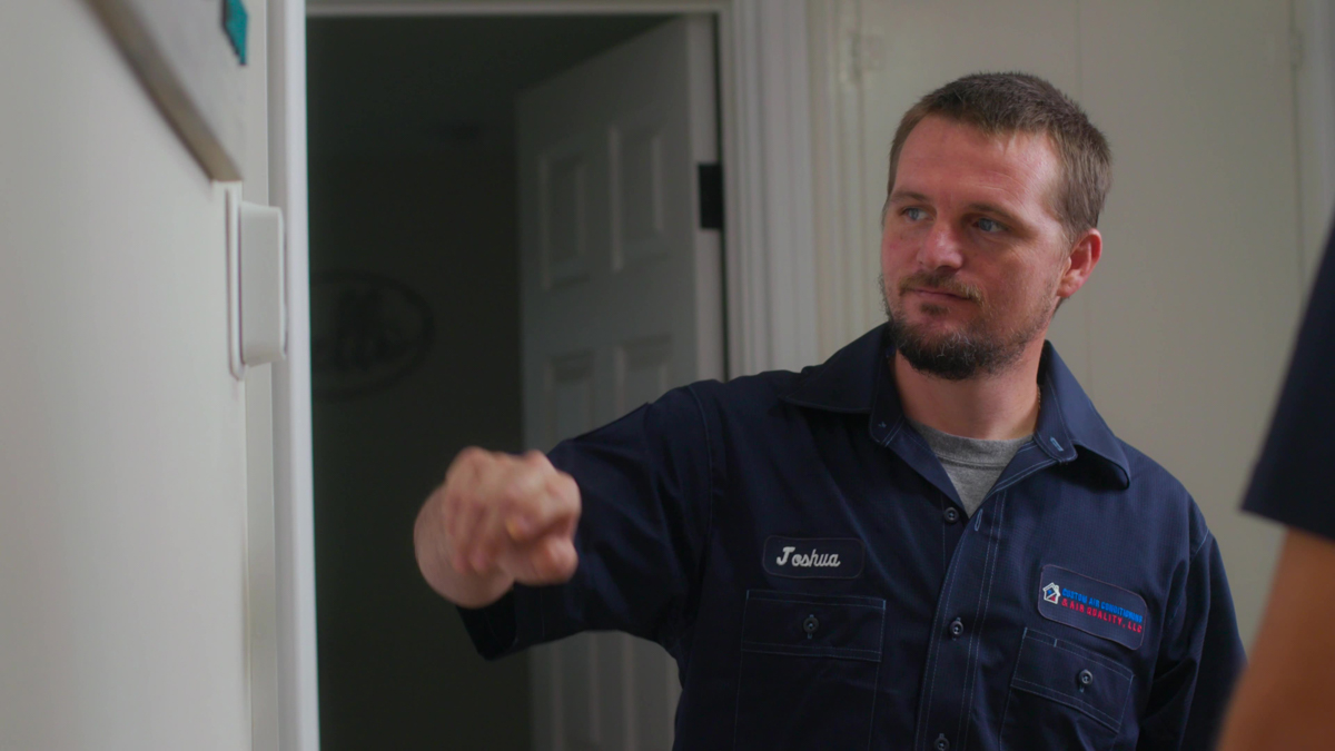 Custom air conditioning and air quality technician fine tuning thermostat settings during a service visit