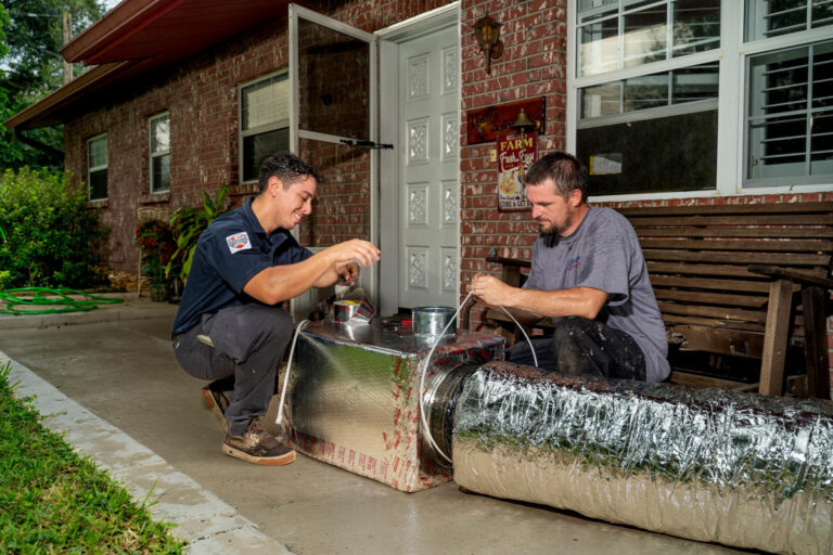 Custom Air Conditioning 2 Two Custom Air Conditioning Air Quality technicians work on sealing an insulated air duct with metallic tape 768x512 1