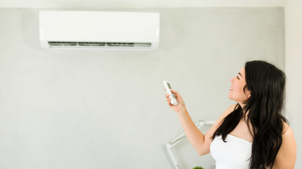 Mini-Split AC Systems: Best Brands, Efficiency, and Choosing the Right One 4 a woman adjusting the temperature on a ductless mini split ac unit with a remote control 1024x576 1